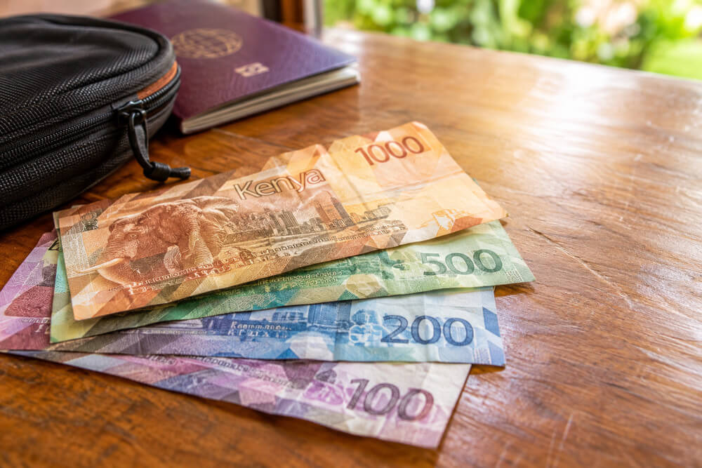 Kenijskie banknoty na stole obok paszportu i podróżnego etui