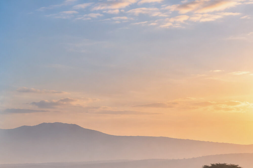 Zamglone wzgórza nad sawanną w porannym świetle Kenii